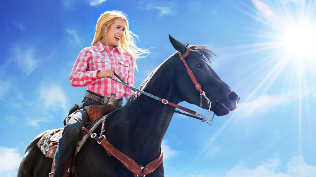 The primary actor from Walk. Ride. Rodeo., a movie on Netflix. She is setting on a horse with a big smile and the sun shinning in the background.