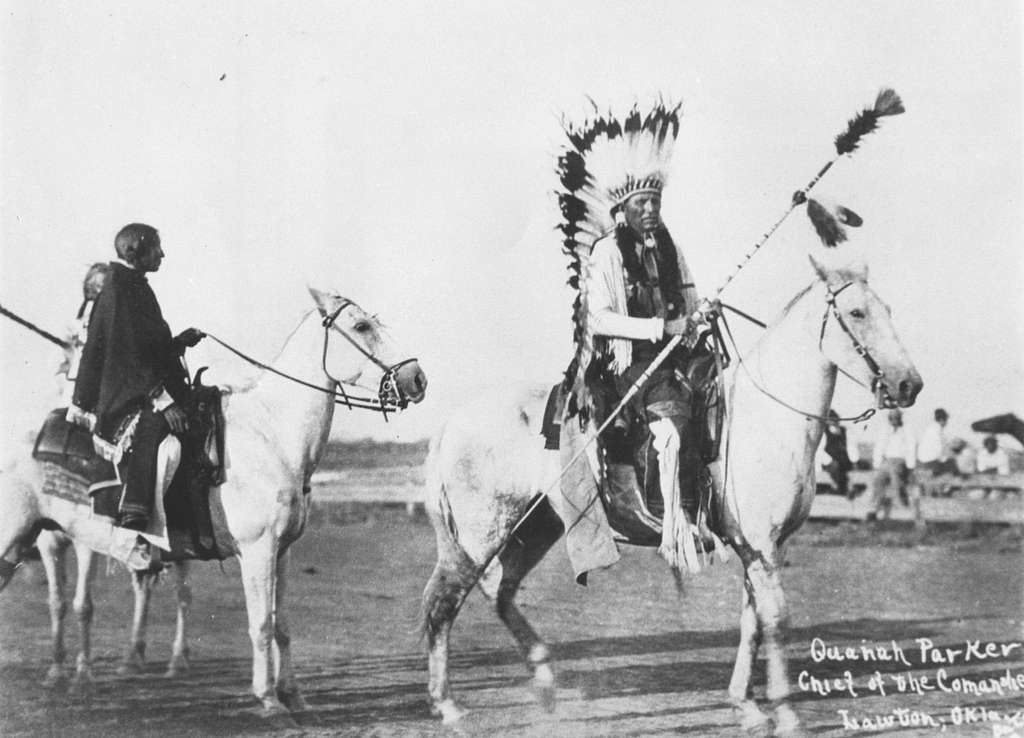 A black and white photo of a Native American Indian riding a horse.