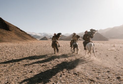 Three Native American horses riding in the desert.